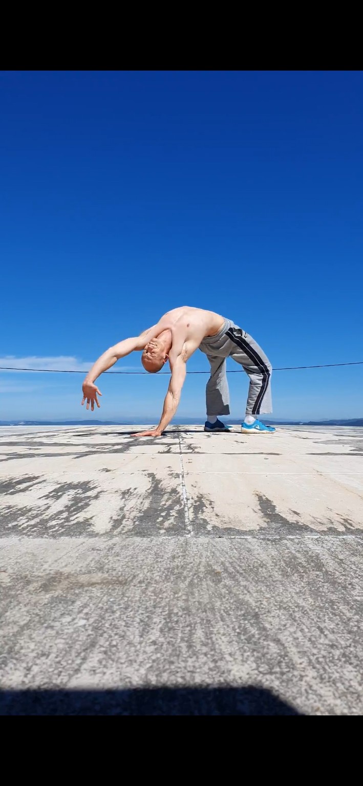Anthony practising a one-arm bridge outdoors, demonstrating mobility and strength